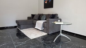 A modern living room with a grey sectional sofa, a glass coffee table, and a black and white marble floor. - 4 minutes by car from the beach new modern apartment in Rhodes town (Rodos)