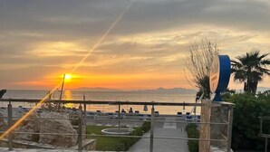 A sunset view with a beach and a palm tree. - 4 minutes by car from the beach new modern apartment in Rhodes town (Rodos)