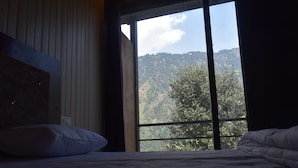 Un dormitorio con un ventanal que ofrece vistas a una ladera boscosa.