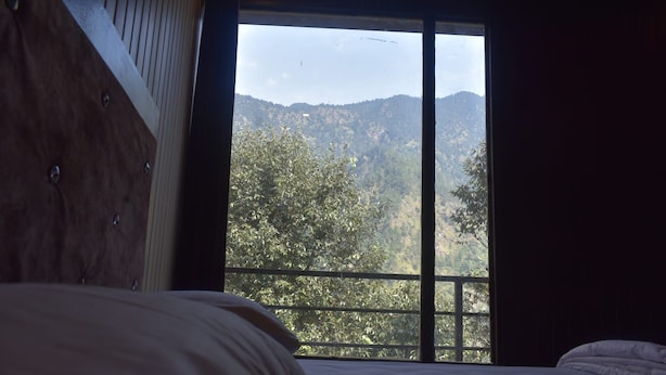Un dormitorio con un ventanal que ofrece vistas de un paisaje montañoso.