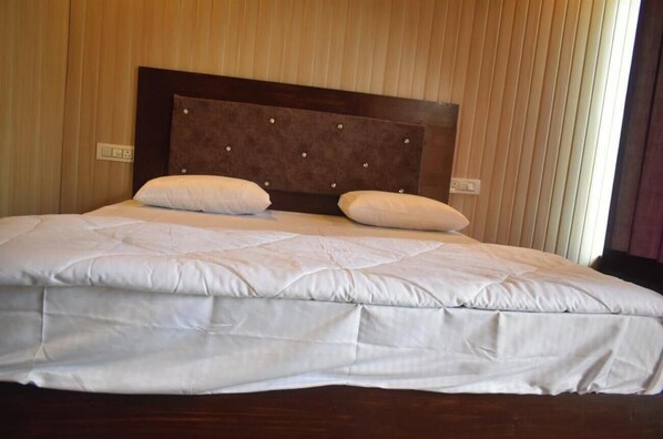 A neatly made bed with a headboard, white bedding, and two pillows.