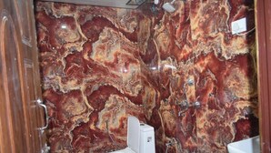 Un baño con pared de mármol, inodoro y zona de ducha.