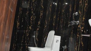 Un baño con inodoro, un cubo morado y una ducha.