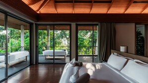 A modern hotel room with a large bed, a sitting area with a bench, and a view of a lush garden through large windows. - Princess Maria - 6BR seaview villa in guarded estate, 250m from Kata Noi Beach (Tambon Karon)