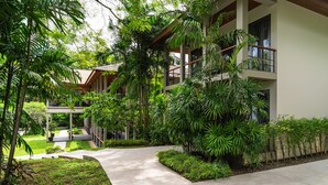 A modern building with a covered outdoor area, surrounded by lush greenery and a concrete pathway. - Princess Maria - 6BR seaview villa in guarded estate, 250m from Kata Noi Beach (Tambon Karon)
