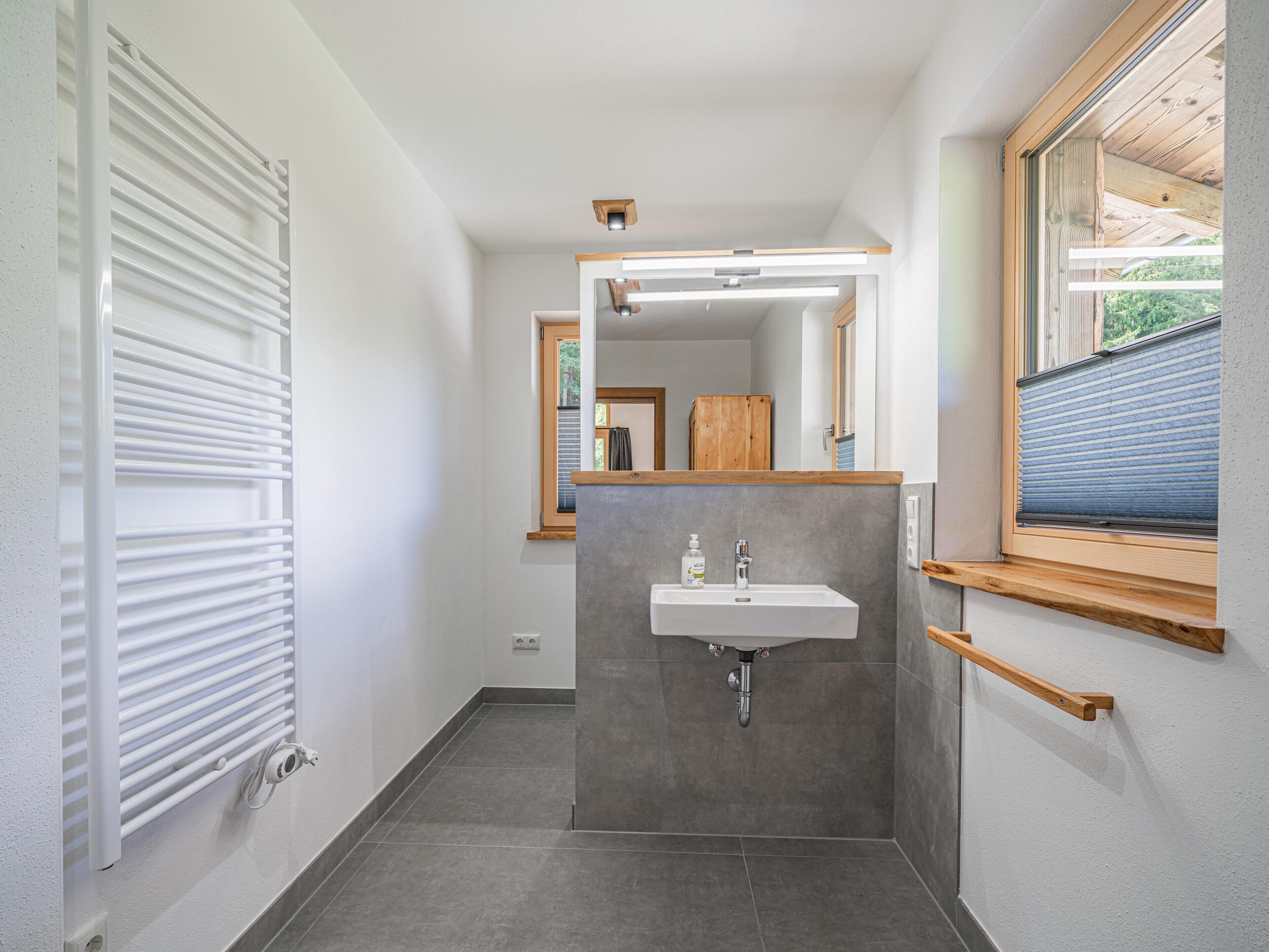 A modern bathroom with a built-in sink, a mirror, and a window.