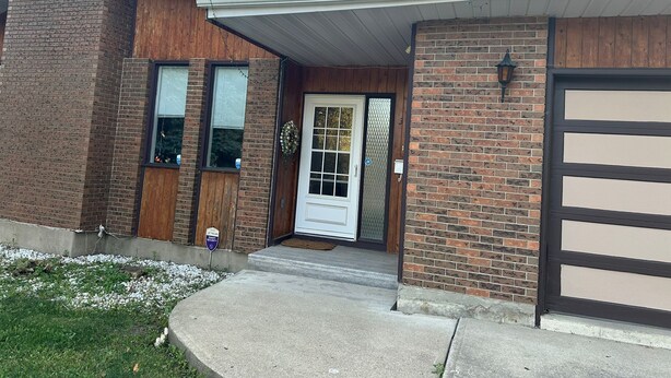 A two-story house with a brick exterior, a front door, and a garage. - 1500 Sqft Entire Basement Private Suite - Extra Spacious & Cozy (Saskatoon)
