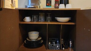 A compact kitchen area with a coffee machine, a kettle, and various kitchenware on shelves. - 1500 Sqft Entire Basement Private Suite - Extra Spacious & Cozy (Saskatoon)