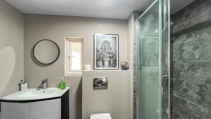 Un bagno moderno con box doccia in vetro, un water bianco e un lavabo con piano in marmo.