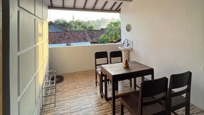 A covered patio with a wooden table and chairs, a sink, and a view of a residential area.