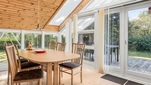 Un comedor con mesa y sillas de madera, ventanas amplias y vistas al exterior.