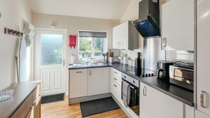 A modern kitchen with white cabinets, stainless steel appliances, and a black countertop. - 3 bedroom accommodation in Brigg (Brigg)