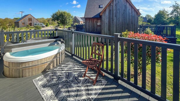 A wooden deck with a hot tub, a chair, and a patterned rug. - 3 bedroom accommodation in Brigg (Brigg)