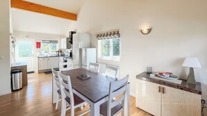 A modern kitchen with white cabinets, a wooden dining table, and a countertop with a lamp. - 3 bedroom accommodation in Brigg (Brigg)
