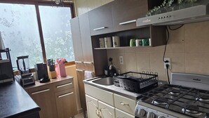 A modern kitchen with a gas stove, a built-in oven, and a window providing natural light. - Cozy apartment near the GNP stadium (Ciudad de México)