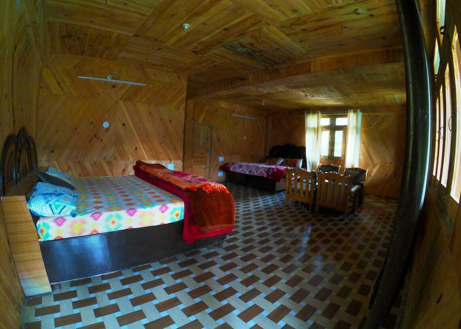 A wooden cabin with two beds, a small table, and a chair.
