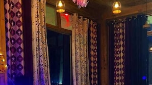 A room with patterned curtains, a sofa, a small table, and hanging lights.