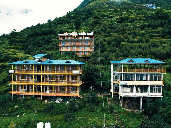 Un hôtel à plusieurs étages, doté de balcons, situé dans une région montagneuse verdoyante.