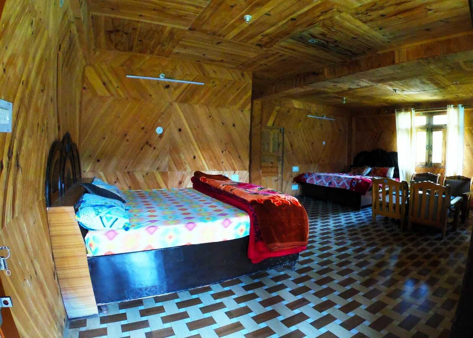 A wooden cabin with two beds, a dining area, and a checkered floor.