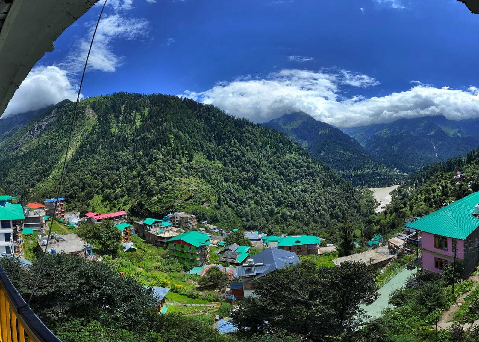 A mountainous village with traditional houses, a river, and a clear sky.