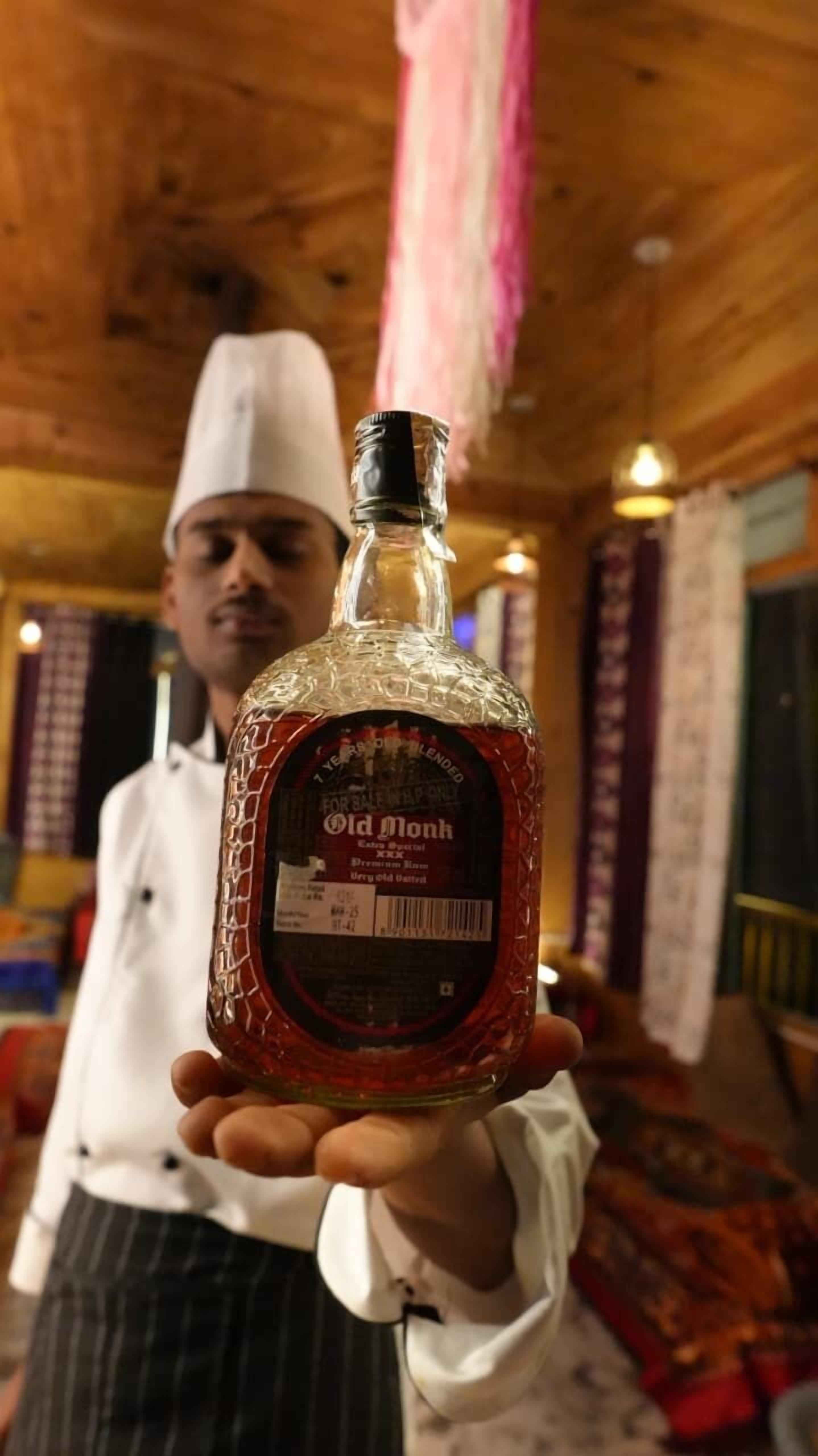 Una persona sosteniendo una botella de whisky Old Monk.