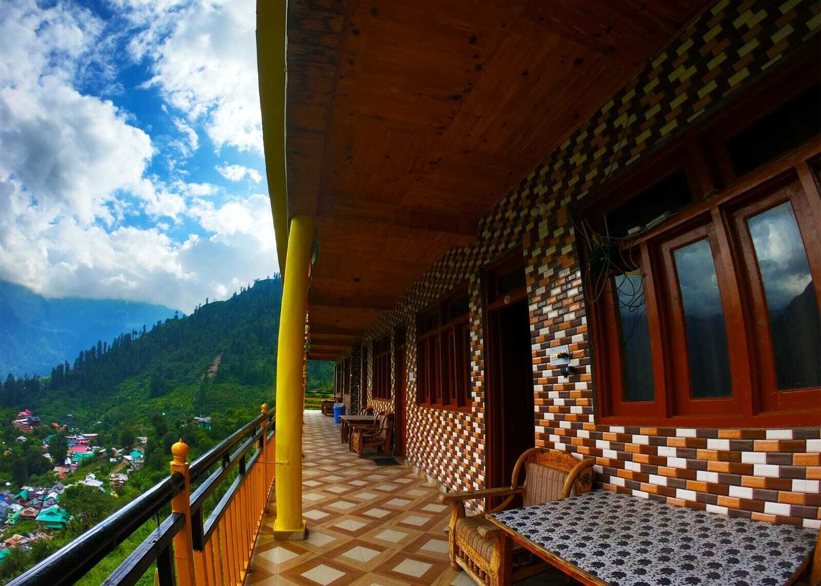 A covered balcony with a wooden ceiling, patterned walls, and a view of a mountainous landscape.
