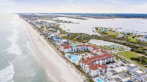 Ett flygbildsbild av ett hotell vid kusten med flera byggnader, en strand och en stor swimmingpool.
