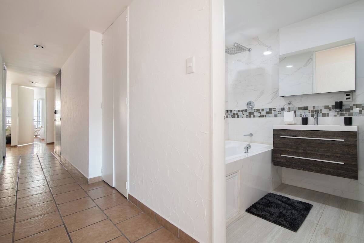A modern bathroom with a white sink, dark wooden vanity, and a tiled shower area.