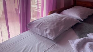 A bedroom with a bed, pillows, and sheer curtains. - Epanomi apartments (Epanomi)
