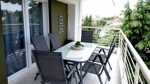 A balcony with a table and chairs, a small plant, and a railing. - Epanomi apartments (Epanomi)