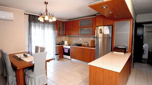 A modern kitchen with wooden cabinets, a built-in oven, and a stainless steel refrigerator. - Epanomi apartments (Epanomi)