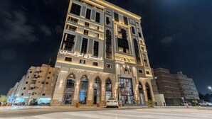 Um hotel com vários andares, uma entrada em arco destacada e sinalização iluminada.