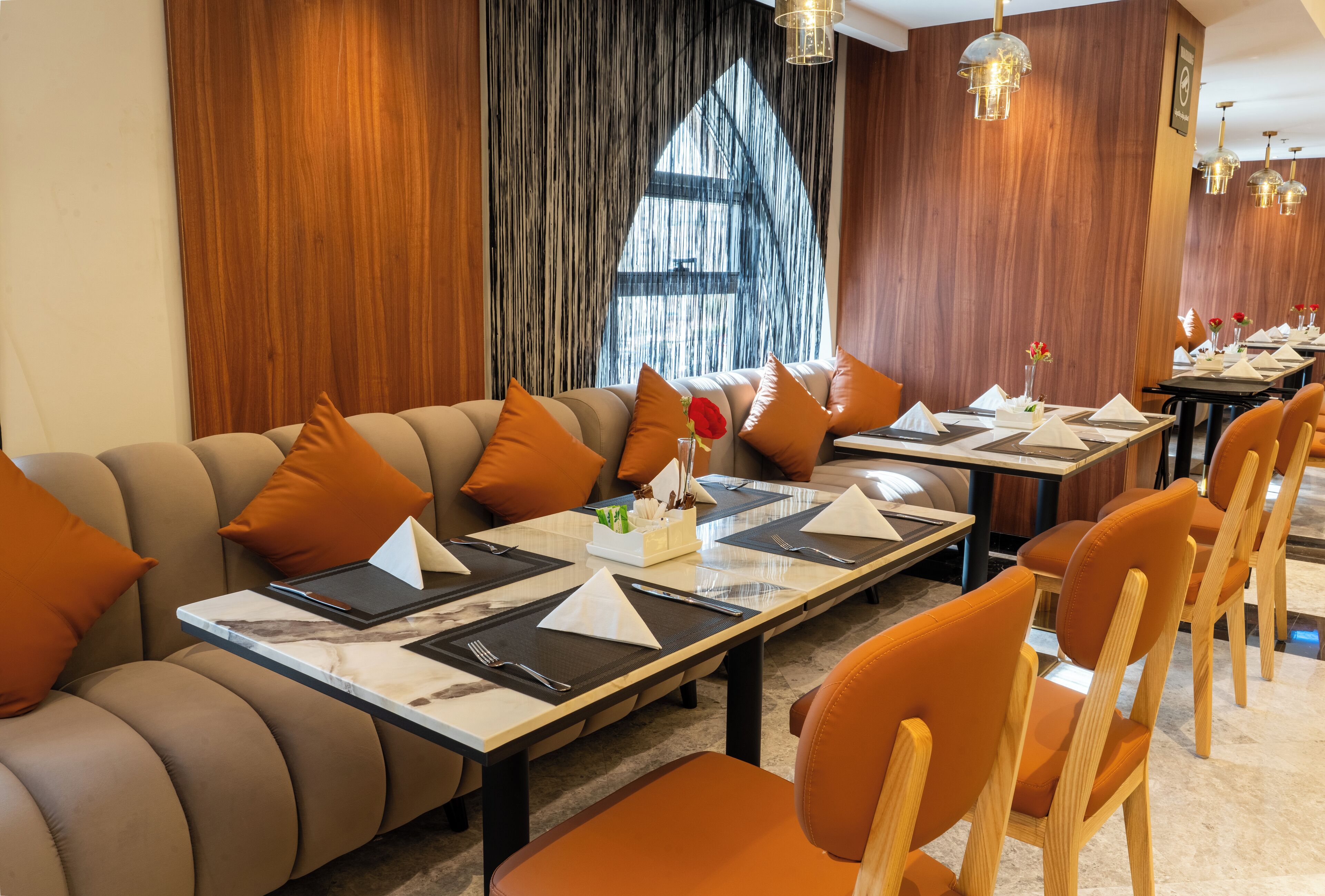 Ein Restaurant mit einem langen Esstisch, gepolsterten Sitzgelegenheiten und Holzdetails.