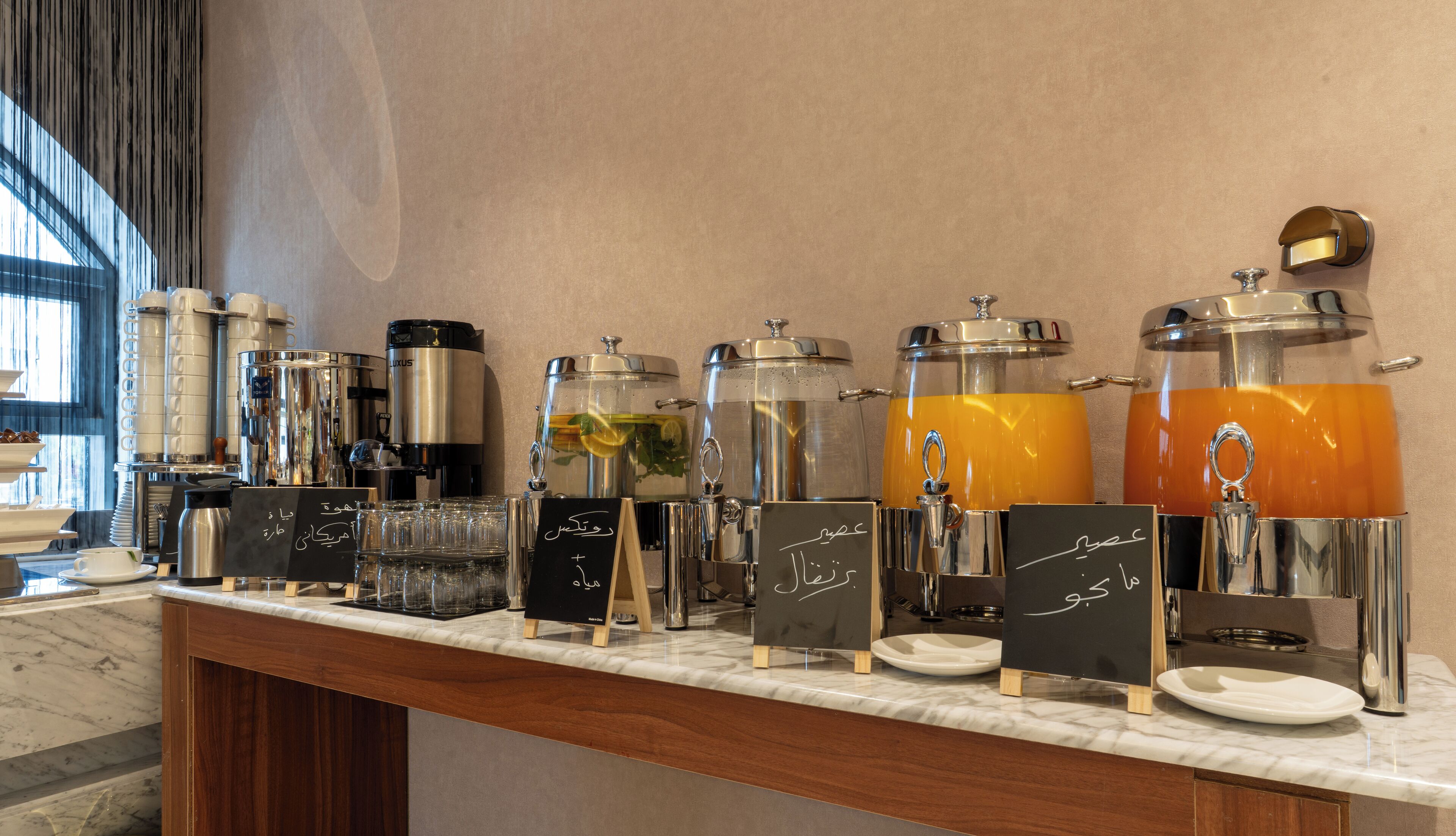 Ein Getränkeausgabe mit mehreren Spendern und Kaffeeautomaten, darunter eine Luxus Kaffeemaschine, auf einer Marmorplatte.