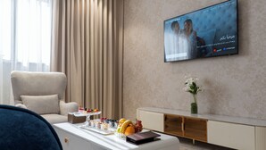 Uma sala de estar moderna com televisão de tela plana na parede, um sofá confortável, uma mesa de centro com lanches e um vaso decorativo.