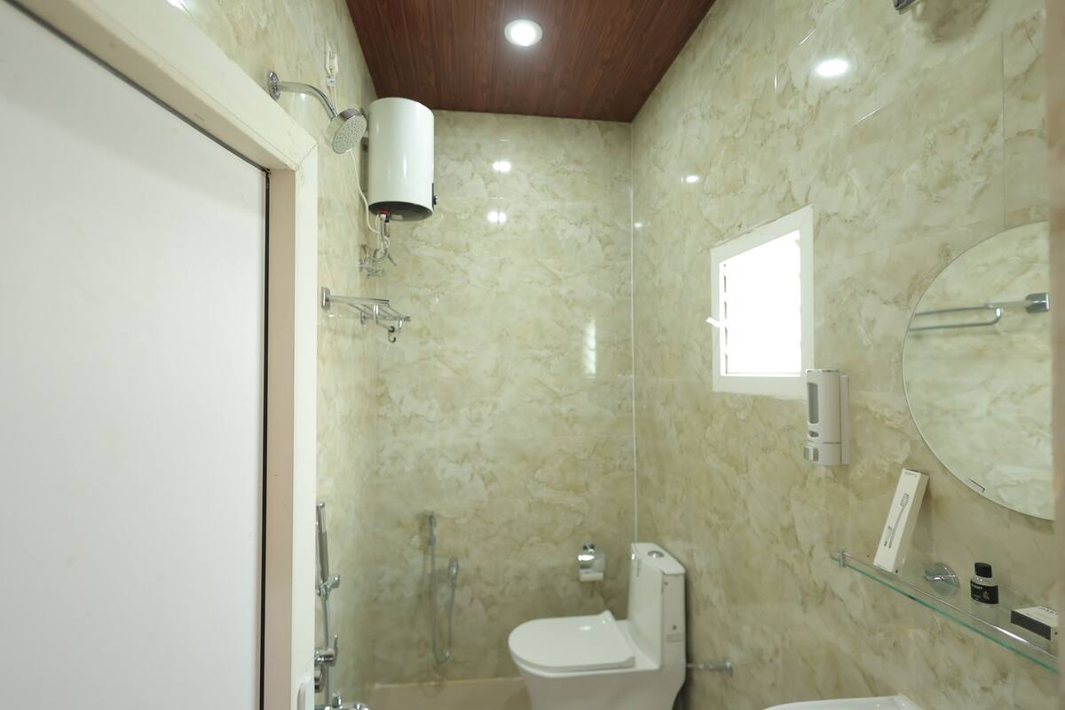 A bathroom with a toilet, bidet, and glass shelf with toiletries.