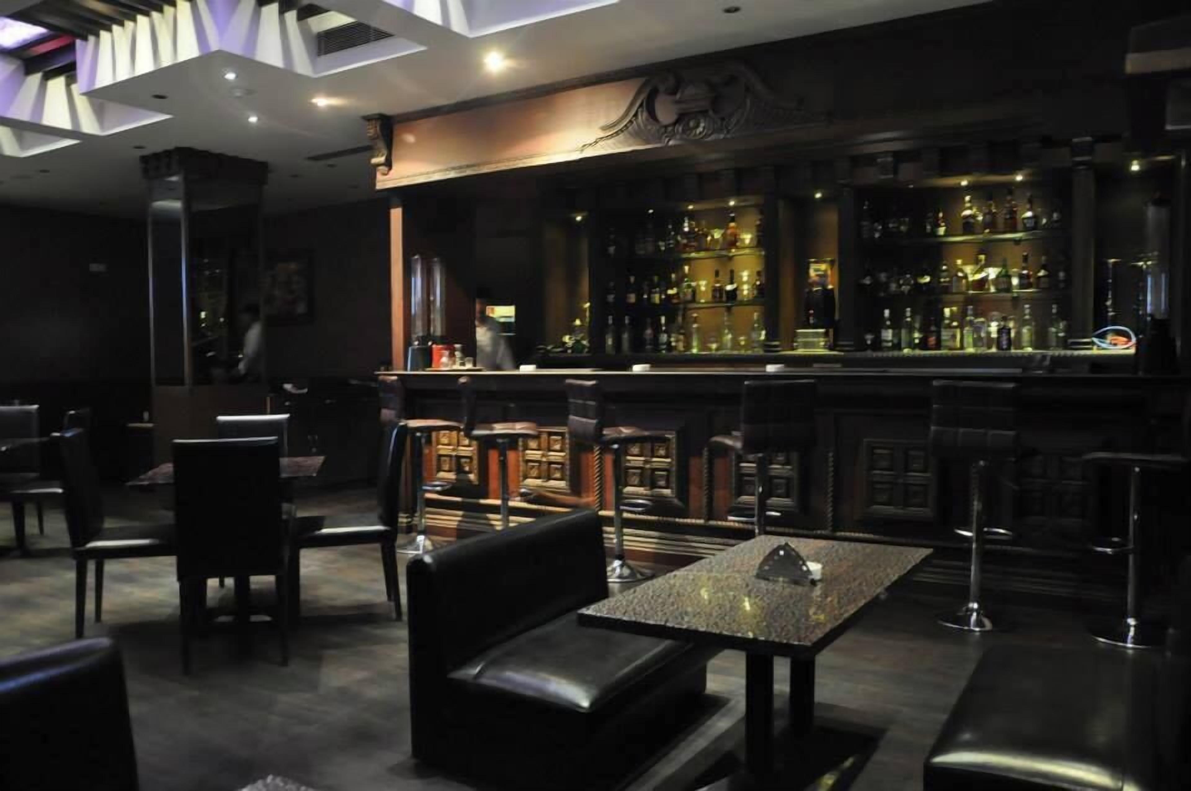 Eine Bar mit Theke, Barhocker und einer Sitzgruppe mit Tisch und Stühlen.