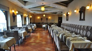 Un restaurante con mesas largas, sillas y una pared con diseño.