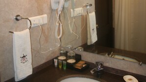 Un baño con lavabo, dos secadores de pelo, un perchero para toallas y un espejo.