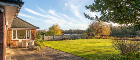 A house with a patio, a lawn, and a view of the countryside.