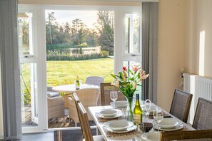 Ein Essbereich im Freien mit Tisch für vier Personen, mit Blick auf einen Garten.