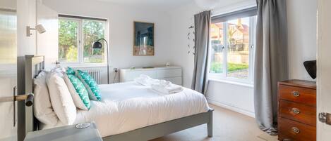 A bedroom with a bed, a dresser, a window, and a painting on the wall.