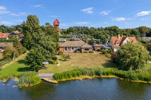 A lakeside property with a house, a dock, and a boat. - Fairway, Thorpeness, Aldeburgh, Suffolk (Thorpeness)