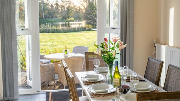 An outdoor dining area with a table set for four, overlooking a garden.