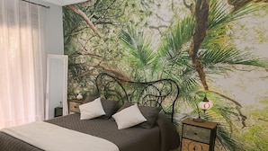 A bedroom with a bed, a nightstand, and a wall mural of a forest scene. - Apto Casares Golf Playa (Casares)