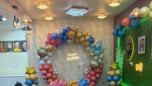 Una habitación con un arco grande de globos y un letrero de neón que dice 'Feliz Cumpleaños'.