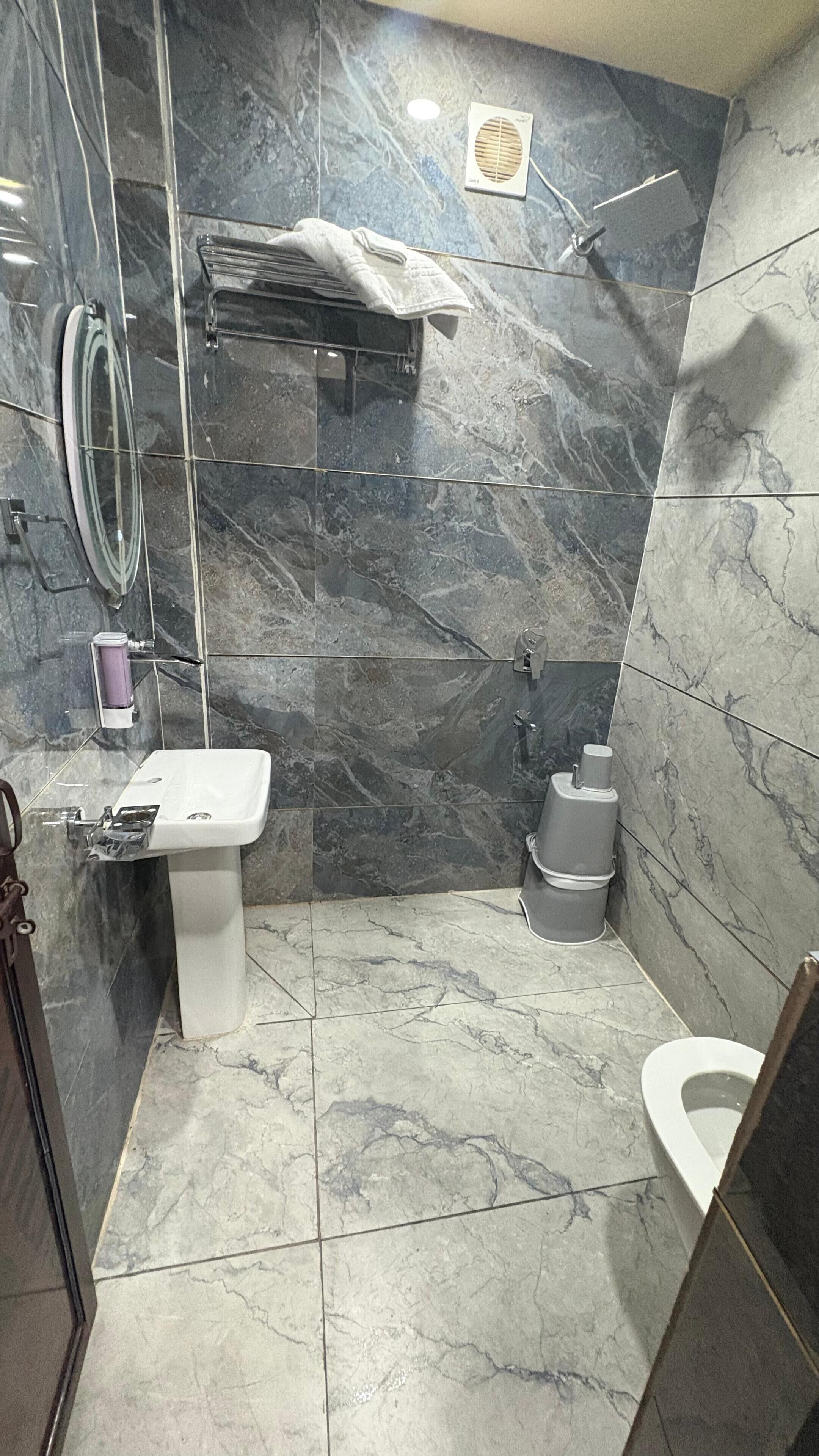 A bathroom with a white sink, a toilet, and a shower area.
