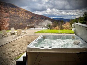 Un jacuzzi con vistas a las montañas y un patio con sillas y una mesa.