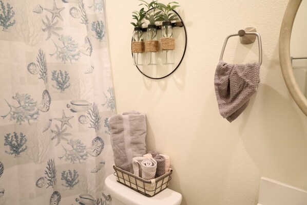 A bathroom with a shower curtain featuring a sea life pattern, a towel rack with a folded towel, and a toilet with a towel basket.