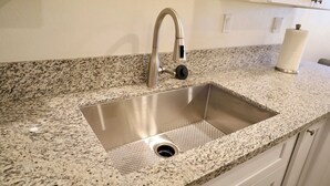 A kitchen with a stainless steel sink, granite countertop, and white cabinets. - 2-bedroom guesthouse in Riverside. Centrally located near CBU,Parkview and 91fwy (Riverside)
